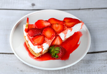 fresh strawberry cheese cake with fruit slices on top in a white ceramic plate