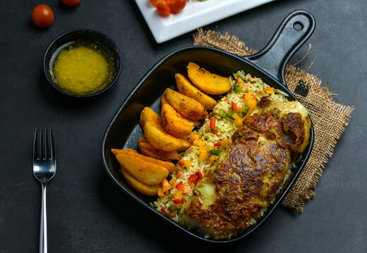 Flaky Grouper fish fillet grilled in garlic sauce served along with fried potato wedges, risotto rice and grilled vegetables.