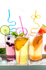 Fruit flavoured spritzer beverages with silly straws, backlit from the sun.