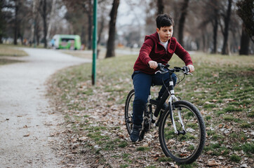 Carefree young boy riding his bicycle in an urban park, experiencing the joy and freedom of childhood outdoors.