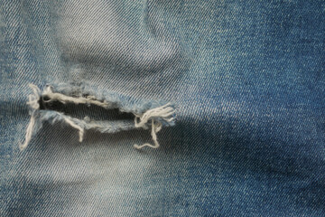 blue jean texture with a hole and ripped threads showing