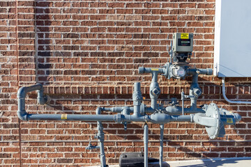 A gray pipe is attached to a brick wall