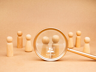 Human resource (HR), hiring, selection, recruitment, CRM, right people and chosen one, concepts. Wooden figures with qualifier teamwork match, digital data, focus by magnifier lens, brown background.