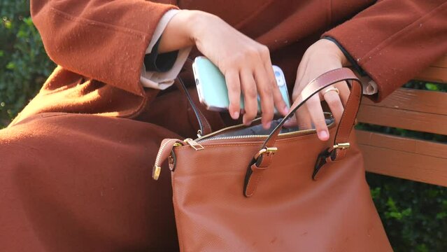  women putting smart phone in her casual purse 