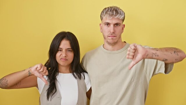 Angry couple's thumbs down gesture, a beautiful fail on a sunny yellow background