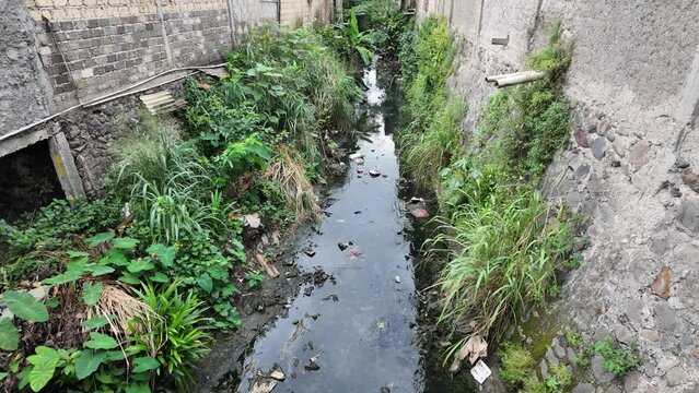 The video starkly portrays a polluted water body choked with trash, suffocating human health. The river stands between seedy houses