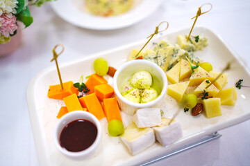 Assorted cheeses with sauce, nuts and grapes on a plate. 