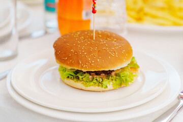A burger on a plate with a funny skewer. 