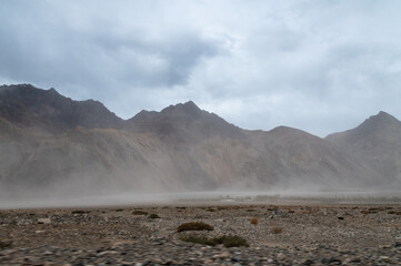 Sand storm with Himalayan mountain and dramatic clouds in the background at Sand Dunes in Hunder,Nubra Valley, Diskit, Ladakh
