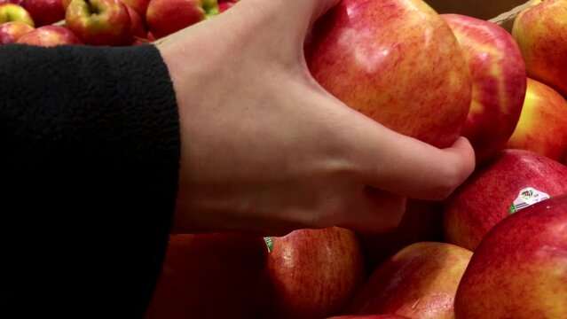 Woman selecting red apple in grocery store