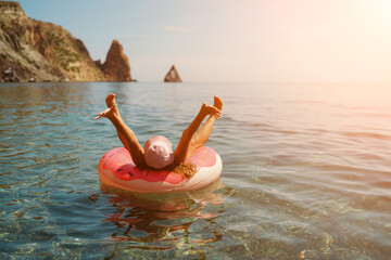 Summer vacation woman in hat floats on an inflatable donut mattress. Happy woman relaxing and enjoying family summer travel holidays travel on the sea.