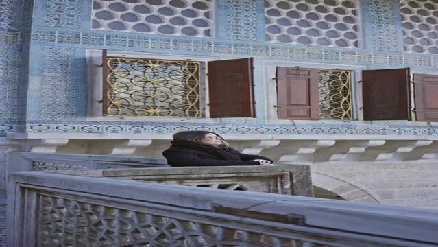 A young woman takes in the stunning ottoman architecture of the topkapi palace in istanbul, turkey.