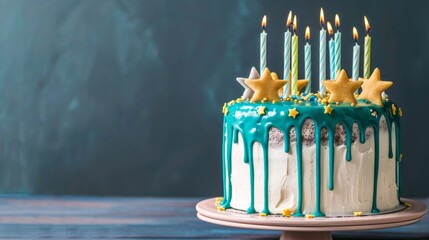 White birthday drip cake with teal ganache, star toppers and fun candles over dark blue background