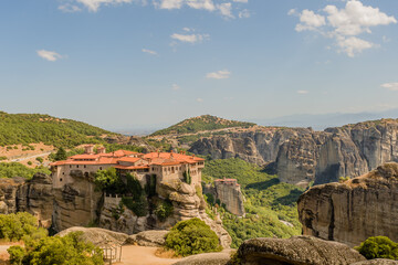 Panoramic landscape featuring a monastery built on massive stone pillars in Meteora Greece