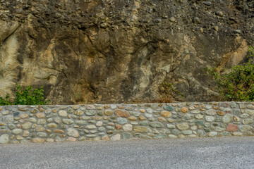Solid stone wall alongside a road demonstrating varied rock textures in Meteora Greece
