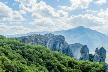 Expansive view of cliffs and mountain ranges under a cloudy blue sky in Meteora Greece