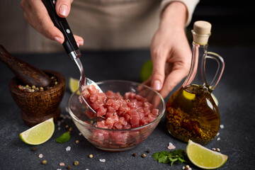 Woman mixing Sliced and chopped tuna fillet and spices in glass bowl cooking traditional tartare