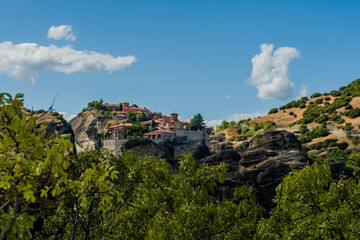 Majestic cliffside monastery with blue skies and green surroundings in Meteora Greece