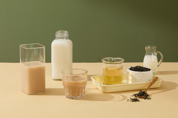 Forest green background against a few glasses and cup filled with drinks inside on beige table. Copy space for texting, photo for beverage, beauty or cosmetic presentation