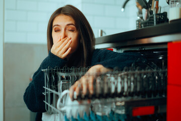 Woman having Problems with a Smelly Dishwashing Machine. Girl disliking the horrible smell coming...