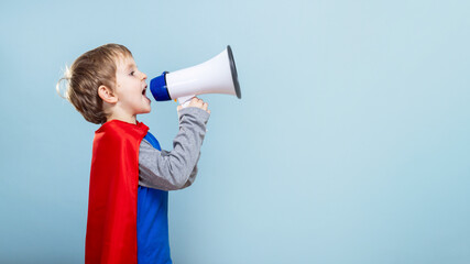 Young boy in superhero costume shouting into megaphone.