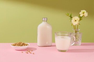 Fresh Soy Milk in unlabeled bottle, a cup of milk, bowl of soybean and a flower vase decorated. Concept stage for product made from natural milk