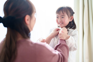 女の子の着替えを手伝うお母さん