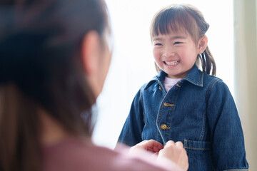 女の子の着替えを手伝うお母さん