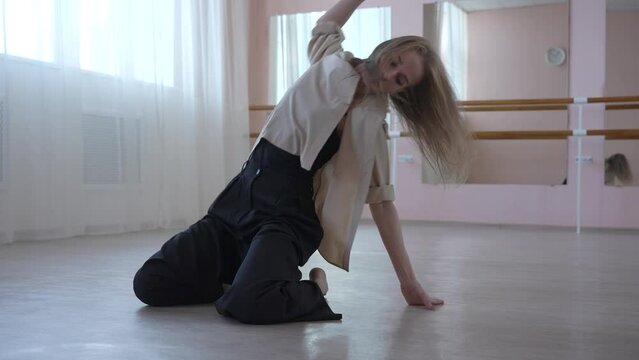 Caucasian woman dancing contemporary on the floor in a ballet class. 