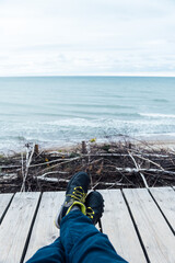 Man sits, dreams and looks at the sea. Rear view, against the backdrop of the sea and waves