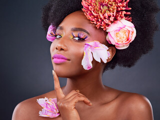 Flowers, portrait and skincare with afro black woman in studio on dark background for natural...
