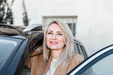 Confident Mature Woman Leaning on Her Car Door Enjoying the View