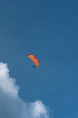 Paraglider soaring high above the sea at sunny day