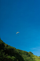 Paragliding in the blue sky over Pandawa Beach, Bali.