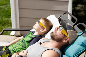Father and son share eclipse watching on a sunny patio