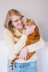 Smiling woman holding ginger cat, joyful indoor moment