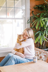 Woman lovingly embracing her ginger cat
