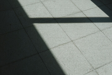 タイルの地面に落ちる窓の影差し込む太陽の日差しのコントラスト