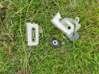 broken tape cassette in the grass flat view - 783560678