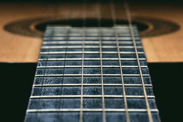 Close up of old acoustic guitar fretboard with selective focus in the center. Neck perspective with blurred sound hole and strings. Music concept. - 783564883