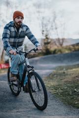 A young man in casual attire is leisurely riding his bike on a scenic park path, enjoying the outdoors.