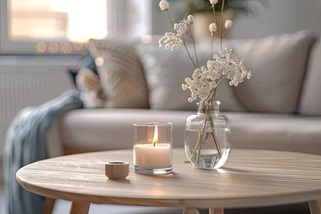 Fotobehang A Wooden Round Table with a Burning Candle and Fresh Flowers in a Glass Vase, Depicting a Modern Home Interior Design of a Living Room in a Cozy Home Concept. A Detailed Photograph.  © Yi