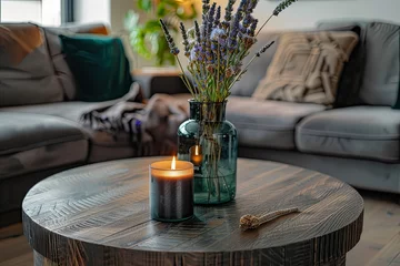Fotobehang A Wooden Round Table with a Burning Candle and Fresh Flowers in a Glass Vase, Depicting a Modern Home Interior Design of a Living Room in a Cozy Home Concept. A Detailed Photograph.  © Yi
