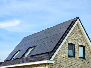 New house with black solar panels on the roof against a sunny sky ,new building with black solar...