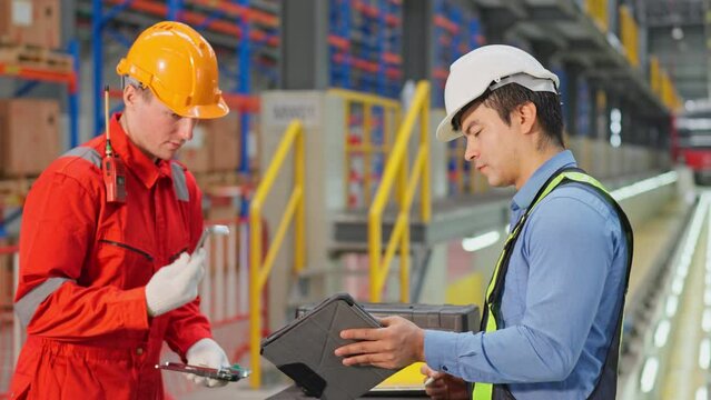 Engineer or technician workers discuss about tools with one hold the tool and the other hold tablet and they stay in front of electrical or metro train in factory workplace.