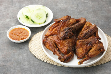 Ayam Bakar, roasted chicken with herbs and spice. Served with chilli paste and cucumber. Indonesian food
