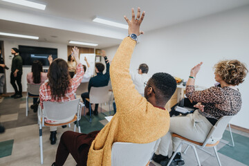 Engaged multiethnic adults raising hands during a lively workshop in a modern office setting....