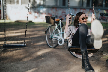 A carefree young adult enjoying time on a swing in an urban park, with a bicycle and graffiti in...