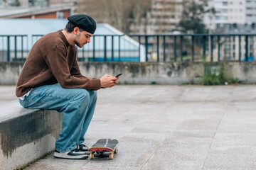 young man on the street with mobile phone and skateboard