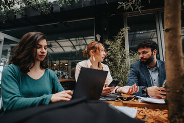 A business team collaborates over laptops during a productive meeting at a cozy coffee bar, sharing ideas and strategies.